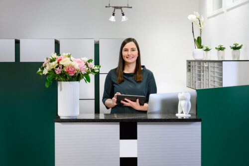 Empfang der Praxis Guntermann - Helferin hinter Tresen mit Tablet