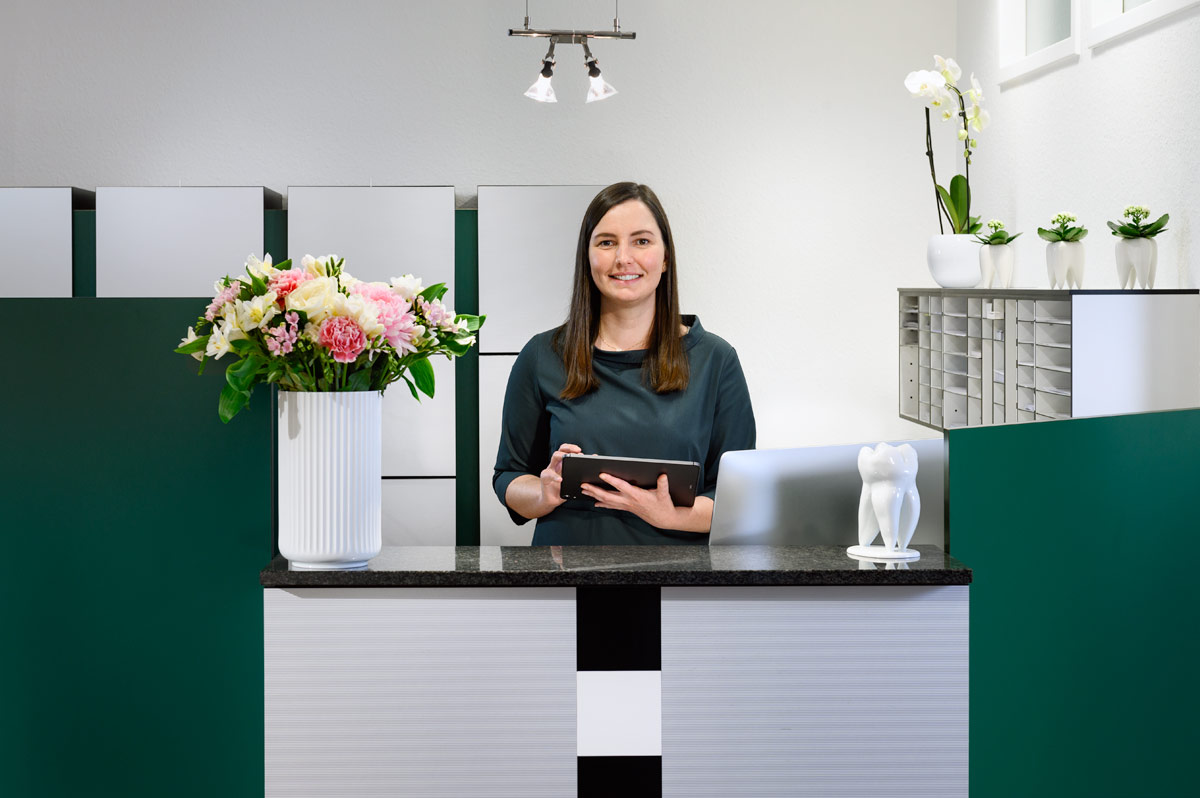 Empfang der Praxis Guntermann - Helferin hinter Tresen mit Tablet
